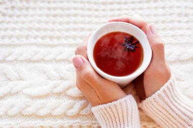 Kadınlar bir fincan çay anason star ile tutar. Güzel kumaş örme desenli arka plan. Rahat sabah evde.