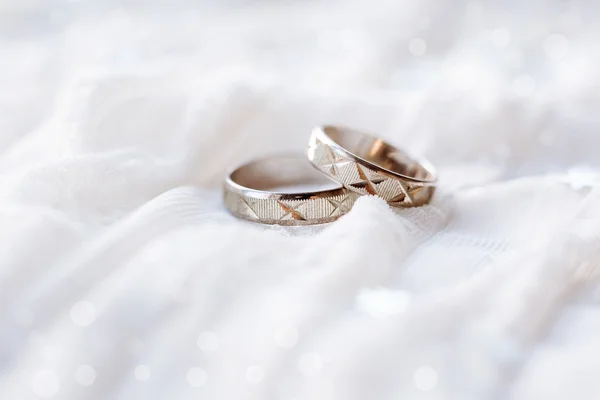 Anillos de boda sobre fondo de tela blanca con bokeh brillante . — Foto de Stock