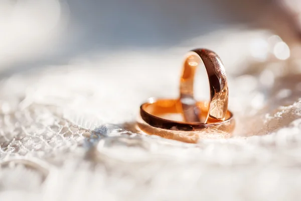 Golden wedding rings on lace silk fabric with buttons. — Stock Photo, Image