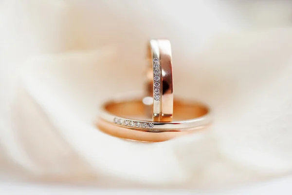 Anillos de boda de oro con diamantes se encuentran en la tela de seda. Símbolo de amor y matrimonio — Foto de Stock