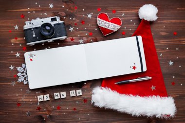 Christmas and New Year background with old fashioned camera, red Santa's hat, notepad and christmas decorations - balls, stars, silver sparkling snowflakes, confetti and words 