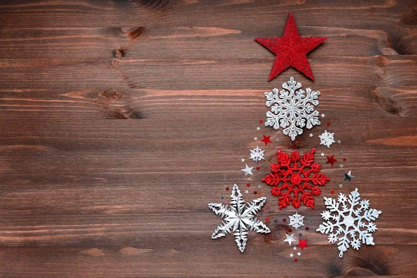 Christmas and New Year background with christmas decorations in shape of fir-tree - balls, stars, silver sparkling snowflakes and confetti on wooden table. Place for your text. — Stock Photo, Image