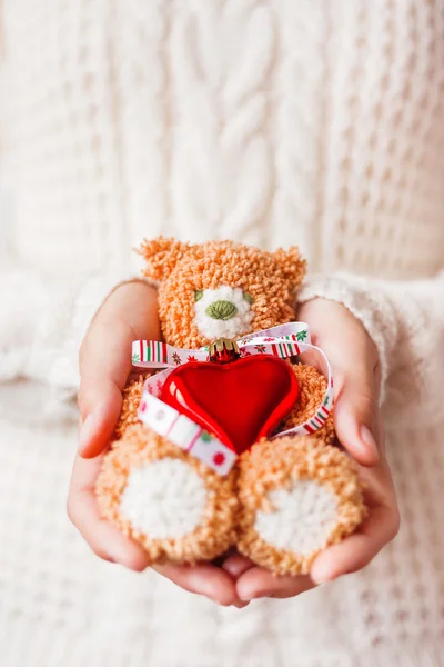 Femme en pull tricoté blanc tenant ours jouet avec ruban de Noël et coeur rouge . — Photo