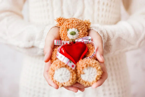 Femme en pull tricoté blanc tenant ours jouet avec ruban de Noël et coeur rouge . — Photo