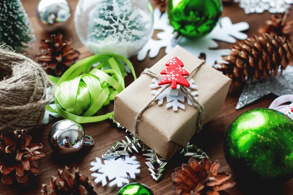 Karácsonyi és újévi háttér bemutatja, szalagok, labdák és más zöld dekorációk-fa háttér. Ajándékot csomagolni, kézműves papír, vörös fenyő. — Stock Fotó