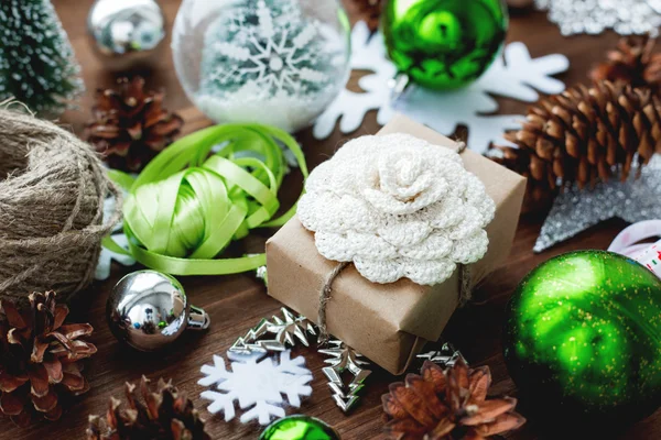 Karácsonyi és újévi háttér bemutatja, szalagok, labdák és más zöld dekorációk-fa háttér. Ajándék kézműves papír, kézi készítésű horgolt virág csomagolva. DIY utat, hogy csavarja a jelen. — Stock Fotó