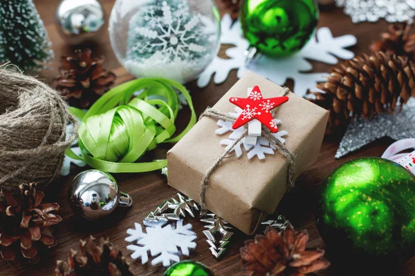 Karácsonyi és újévi háttér bemutatja, szalagok, labdák és más zöld dekorációk-fa háttér. Vörös csillag kézműves papír csomagolva ajándék. — Stock Fotó