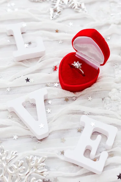 Word LOVE sobre fondo de tela blanca con anillo de diamantes de compromiso en caja de regalo roja. Bueno para tarjetas de San Valentín . — Foto de Stock