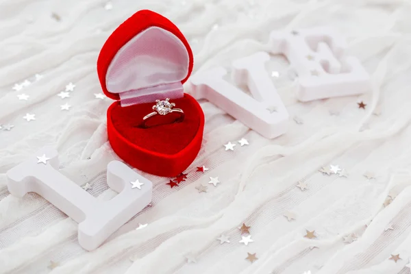 Wortliebe auf weißem Stoffhintergrund mit Verlobungsring in roter Geschenkbox. gut für Valentinstagskarten. Platz für Text. — Stockfoto