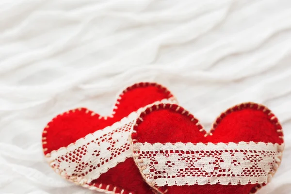 Sfondo in tessuto bianco con ruche.Due cuori in feltro con lacci, simbolo d'amore. Buono per le carte di San Valentino. Posto per testo . — Foto Stock