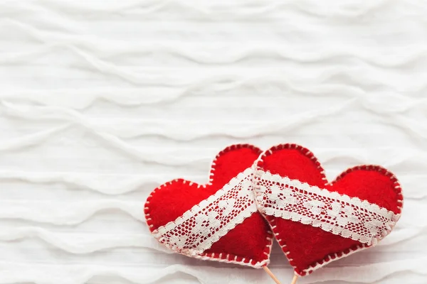 Fond en tissu blanc avec rouche.Deux cœurs en feutre avec des lacets, symbole de l'amour. Bon pour les cartes de Saint-Valentin. Place pour le texte . — Photo