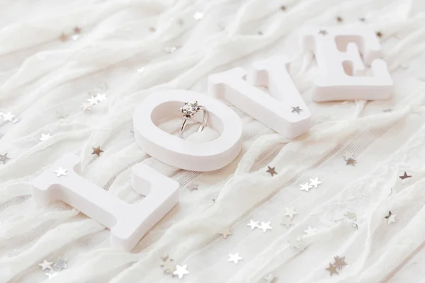 Word LOVE sobre fondo de tela blanca con anillo de diamantes de compromiso. Bueno para tarjetas de San Valentín . — Foto de Stock