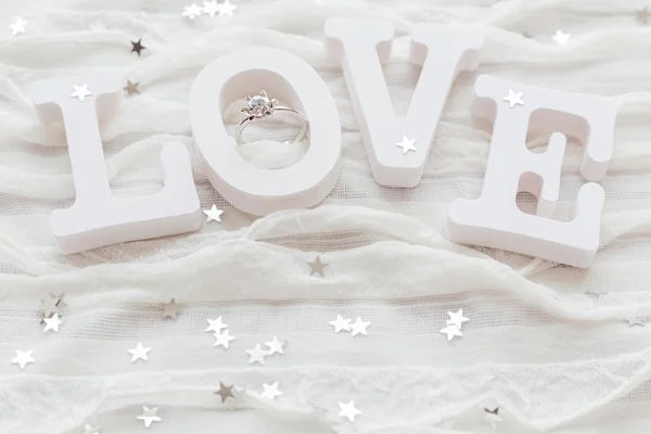 Word LOVE sobre fondo de tela blanca con anillo de diamantes de compromiso. Bueno para las tarjetas de San Valentín. Lugar para el texto . — Foto de Stock