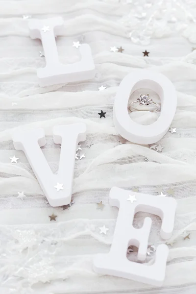 Word LOVE sobre fondo de tela blanca con anillo de diamantes de compromiso. Bueno para tarjetas de San Valentín . — Foto de Stock