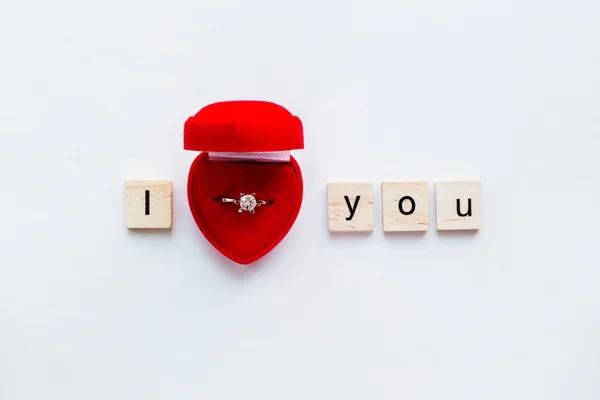 White background with wooden words I LOVE YOU and engagement ring — Stock Photo, Image