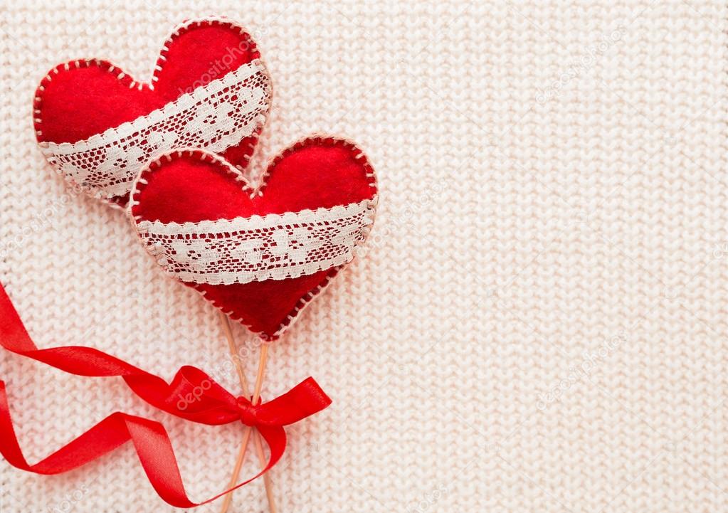 White woven background with two felt hearts with laces, symbol of love.