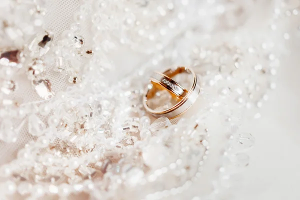 Anéis de casamento dourados em tecido de seda de renda com contas. Vestido de bordado de casamento detalhe . — Fotografia de Stock