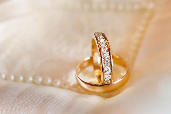 Golden wedding rings with diamonds on silk fabric. Wedding jewelry details. — Stock Photo, Image