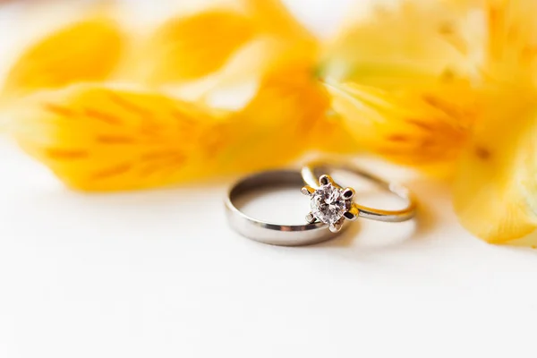 Par de anéis de casamento e noivado com flor de Alstroemeria amarela. Fundo natural com símbolo de amor e casamento. Fecha. Lugar para texto . — Fotografia de Stock