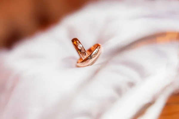 Golden wedding rings with ornament on silk background. Wedding details. — Stock Photo, Image