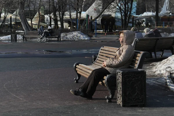 MOSCÚ, RUSIA - 11 de marzo de 2015: Mujer mayor sentada en un banco de madera en Catherine Park en un día soleado —  Fotos de Stock