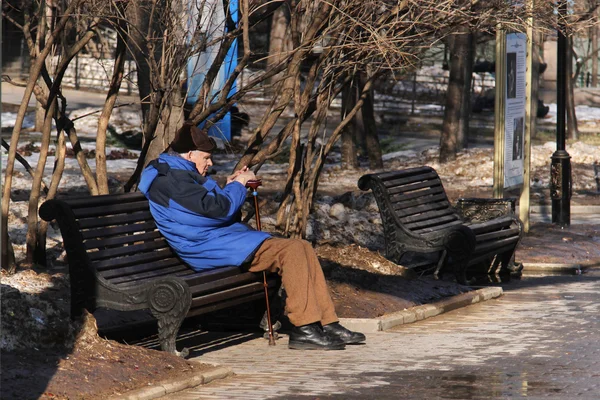 Moscow, Russia - March 11, 2015:Elderly man sitting on wooden bench in Catherine Park on a sunny day