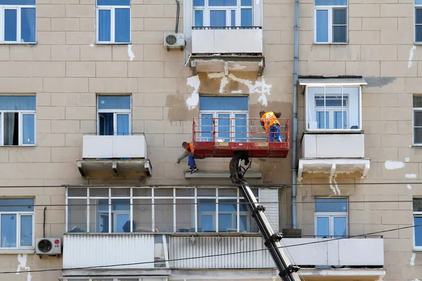 РОССИЯ, МОСКВА - 18 июня 2015 года: Два строителя в ведре крановой техники реконструируют фасад здания в Москве — стоковое фото