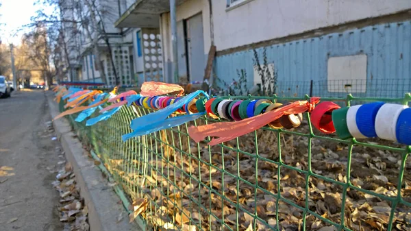 Colorful plastic bottle caps and pieces of plastic bags hang on the fence in the yard