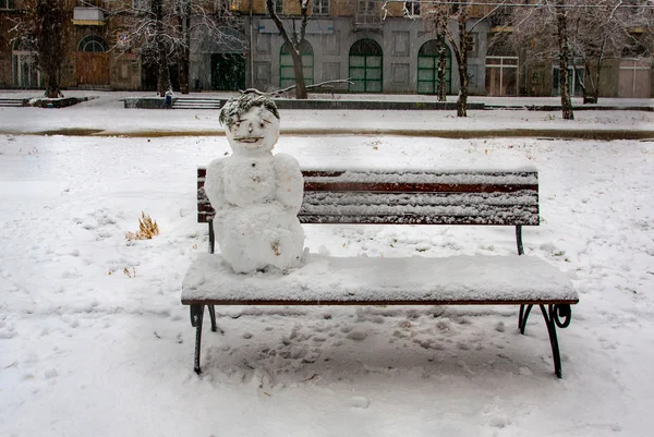 Bonhomme de neige assis sur le banc — Photo