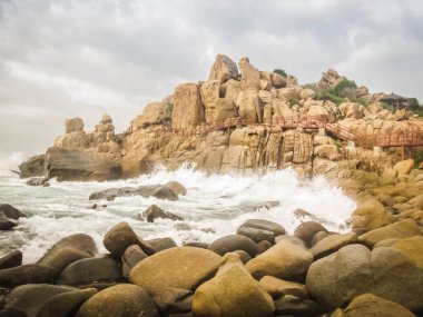 Ninh Thuan, Vietnam 'daki Rai mağarası yakınlarında bulutlu bir günde kayalık bir plajın fotoğrafı.