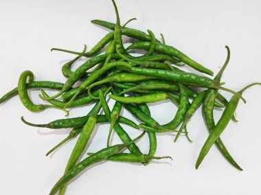 Beyaz arka planda birbirine dolanmış taze, uzun yeşil biberler..