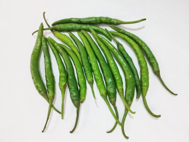 Taze yeşil biberler dikey dizilmiş ve beyaz arka planda hafifçe yelpazelenmiş..