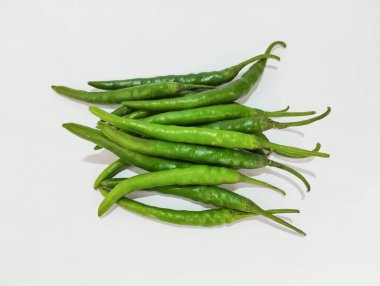 Beyaz arka planda düzgünce istiflenmiş küçük bir yeşil biber yığını.