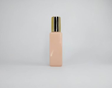 Tek bir şeftali rengi parfüm şişesi, beyaz arka planda altın kapaklı..