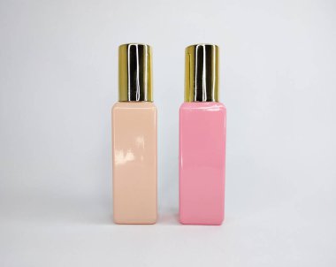 İki küçük parfüm şişesi, bir şeftali ve bir pembe, altın kapaklı..