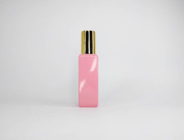 Katı pembe dikdörtgen parfüm şişesi, üzerinde parlak, metalik bir kapak var..