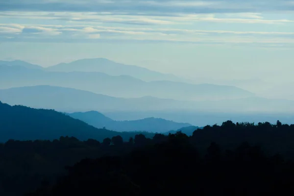 Landscape with silhouettes of blue mountains with mist and cloud in the morning