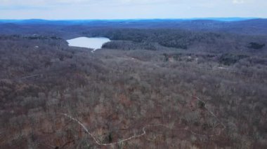 Apalaş Dağları 'nda kışın çıplak ağaç tepe örtüsü ve uzak bir göl olan uçsuz bucaksız bir arazinin insansız hava aracı görüntüleri.