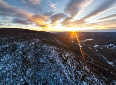 New York 'ta gün batımında Shawangunk Dağları' nın hava aracı görüntüsü. Altın güneş ışığı, Appalachian bölgesindeki dağ sırtlarını ve vadileri aydınlatan kışın dramatik bulutların arasından doğar..