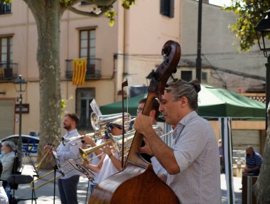 Ulusal Gün olduğu için orkestra şehrin ana meydanında müzik enstrümanları çalıyor. Adam çello, trombon ve trompet çalıyor..