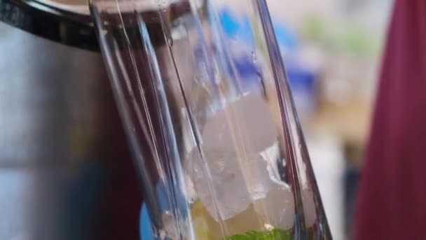 Barista aggiunge ghiaccio pezzi di vetro fette di calce rendendo mojito cocktail alcolico — Video Stock