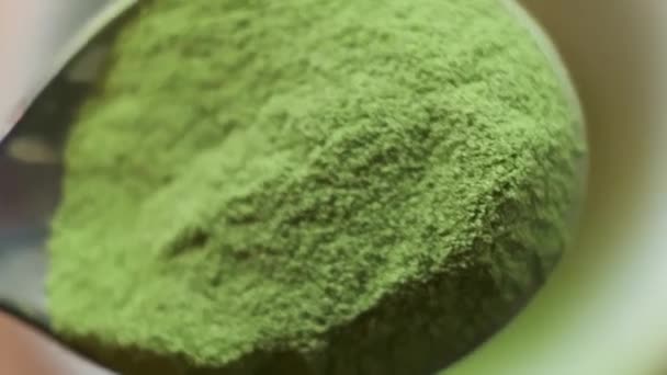 Zeitlupenmakro eines eisernen Löffels mit einer Handvoll Matcha, der in eine Tasse gegossen wird — Stockvideo