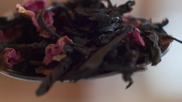 Plan macro au ralenti de cuillère avec une poignée de feuilles de thé, qui sont jetées — Video