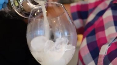 Kız barmen, hazır karışımı bardaktan buzlu bardağa doldurur.