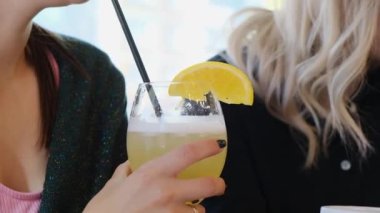 Kafedeki siyah pipetin içinde alkollü kokteyl içen genç bir kız.