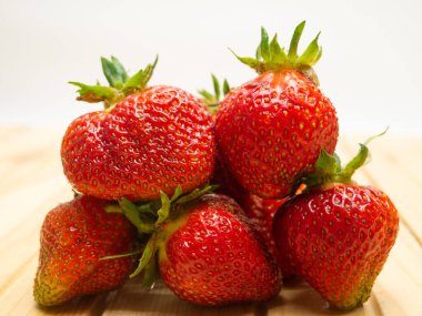 Yapraklı çilekleri yakından çek. Olgun kırmızı böğürtlenler masanın üzerinde duruyor..