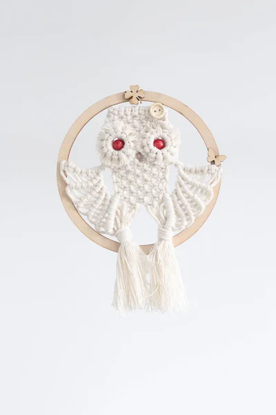 Beyaz arka planda kordon baykuşuyla örülmüş makrame el.