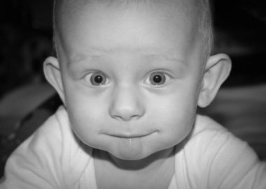 Beş aylık erkek bebek, tek renkli objektife bakıyor.