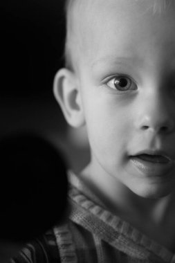 Bir yaşındaki erkek bebek doğrudan kameraya bakıyor, tek renkli görüntü.