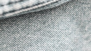 Açık gri kot kumaşın makro çekimini kapat. Karmaşık dokuyu ve dokuma desenini ortaya çıkar.